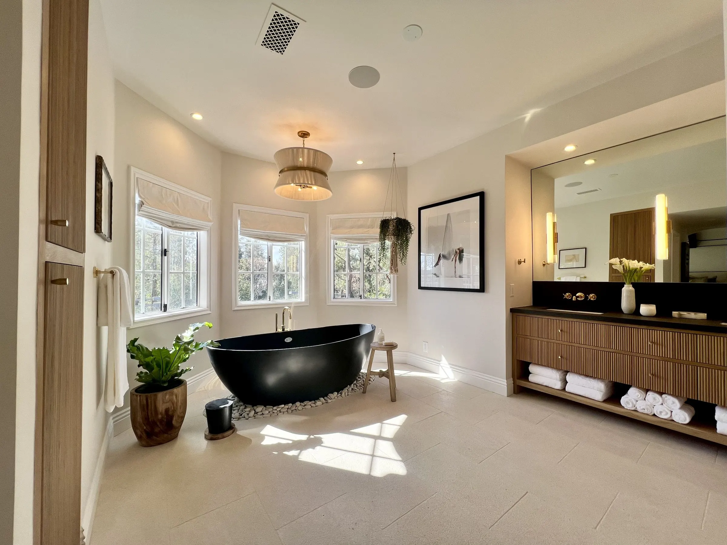 Primary bathroom with a freestanding tub, pendant, and mirror lighting