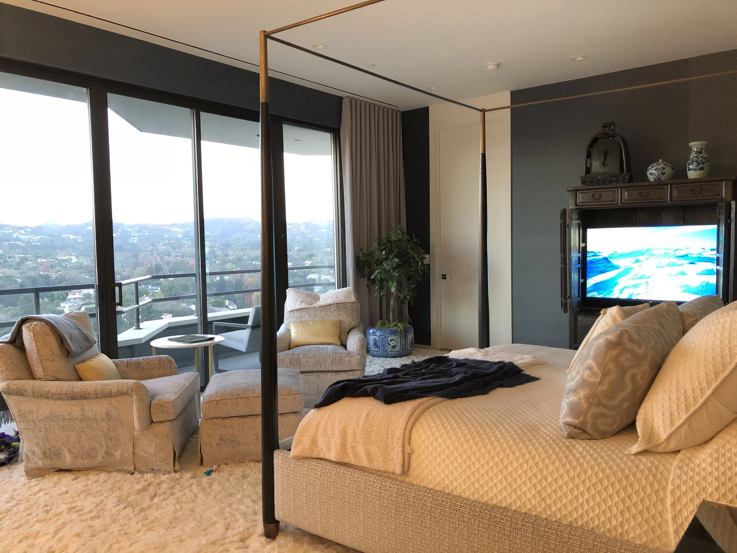 Primary bedroom with a television in an armoire and floor-to-ceiling windows