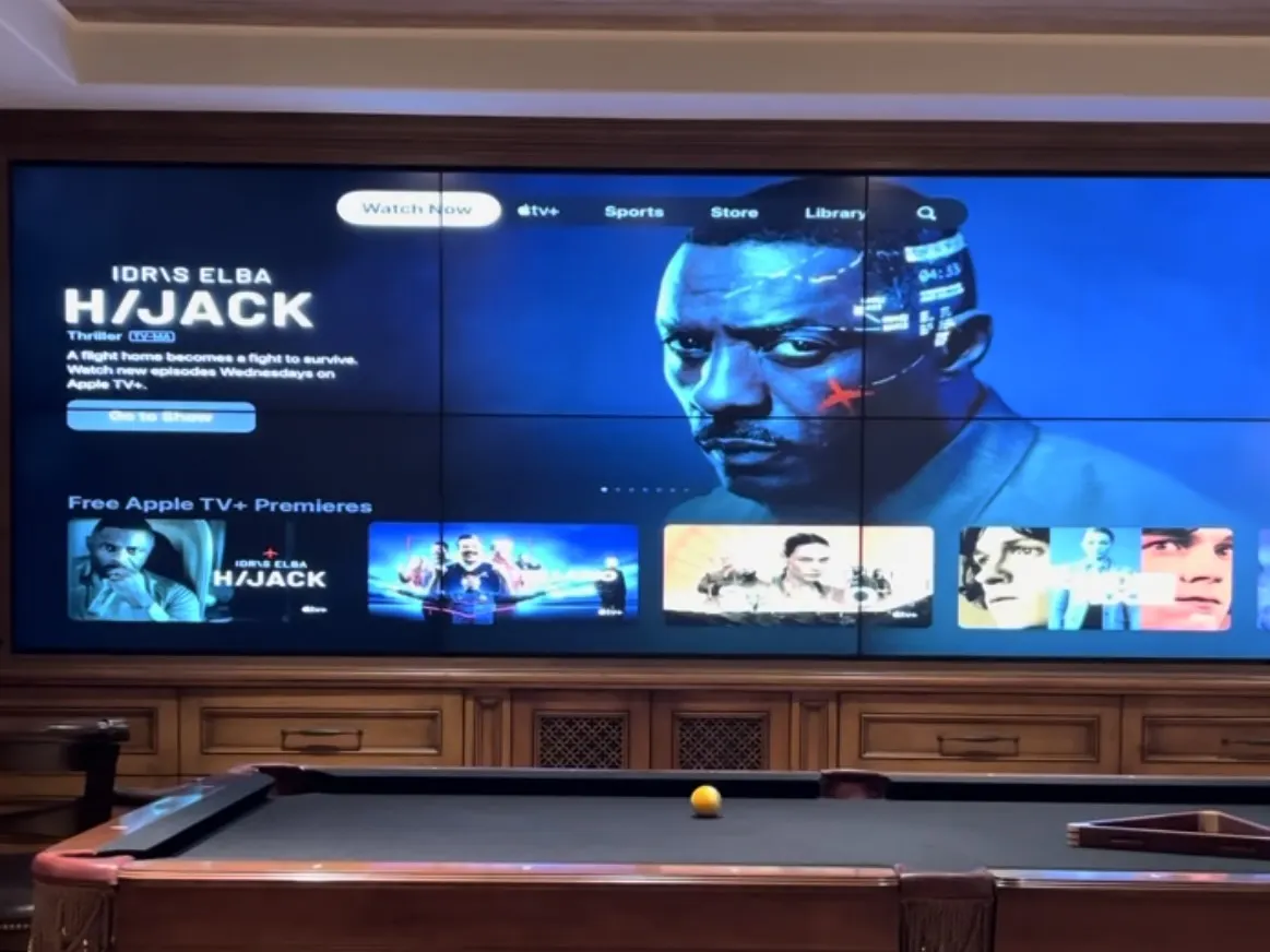 Game room with a wall-size seamless video wall above wood paneling and a billiards table in front