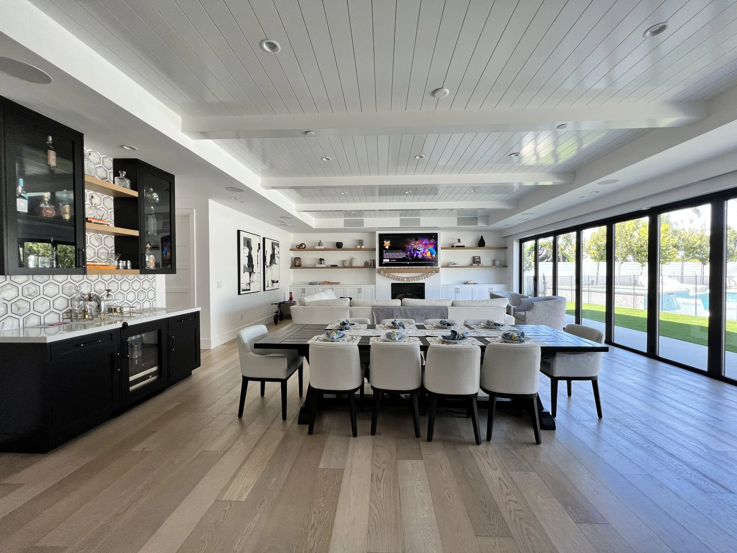 Long great room with dining table, bar, and a display at the far end