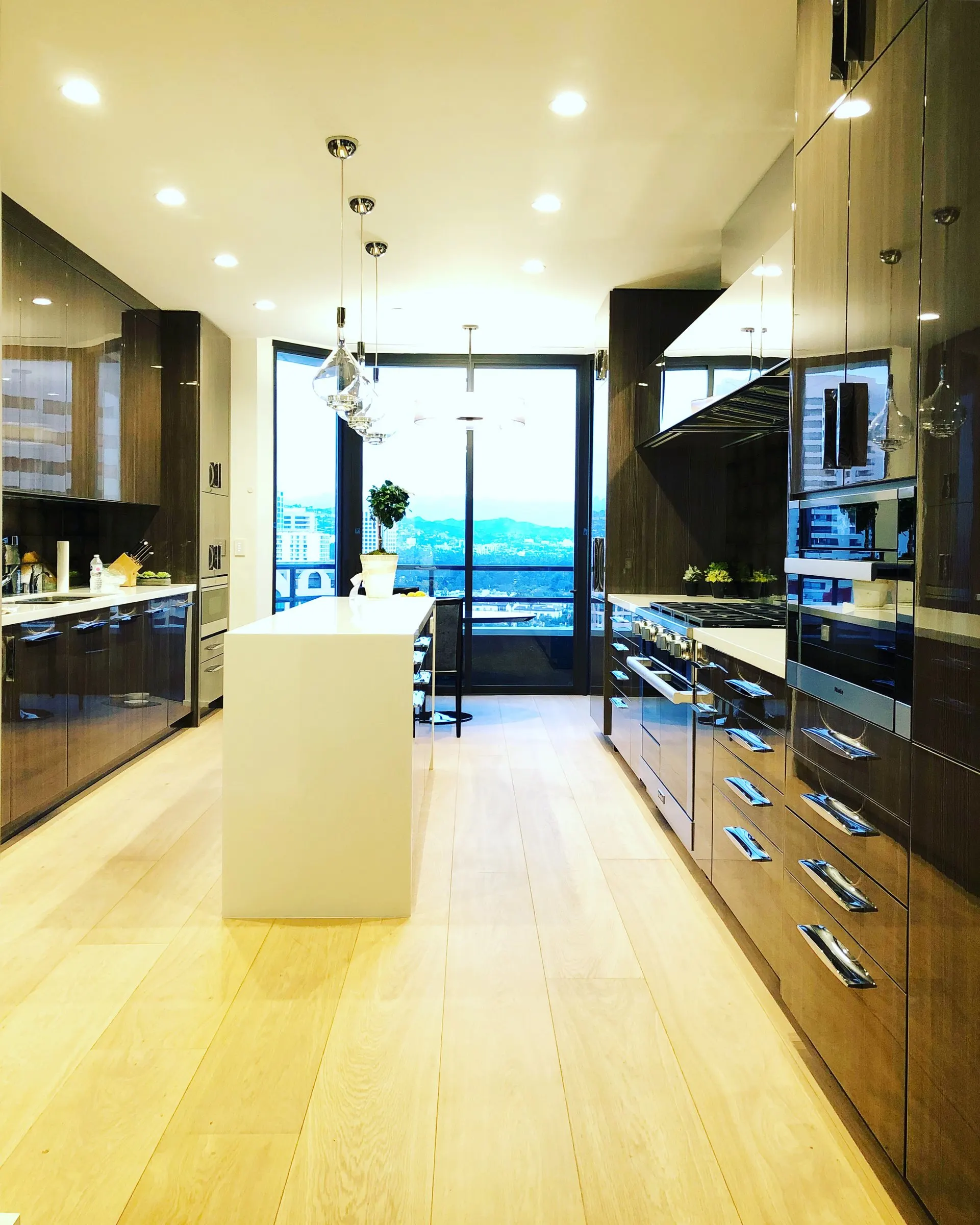 Long kitchen with pendant and recessed lighting and a city view