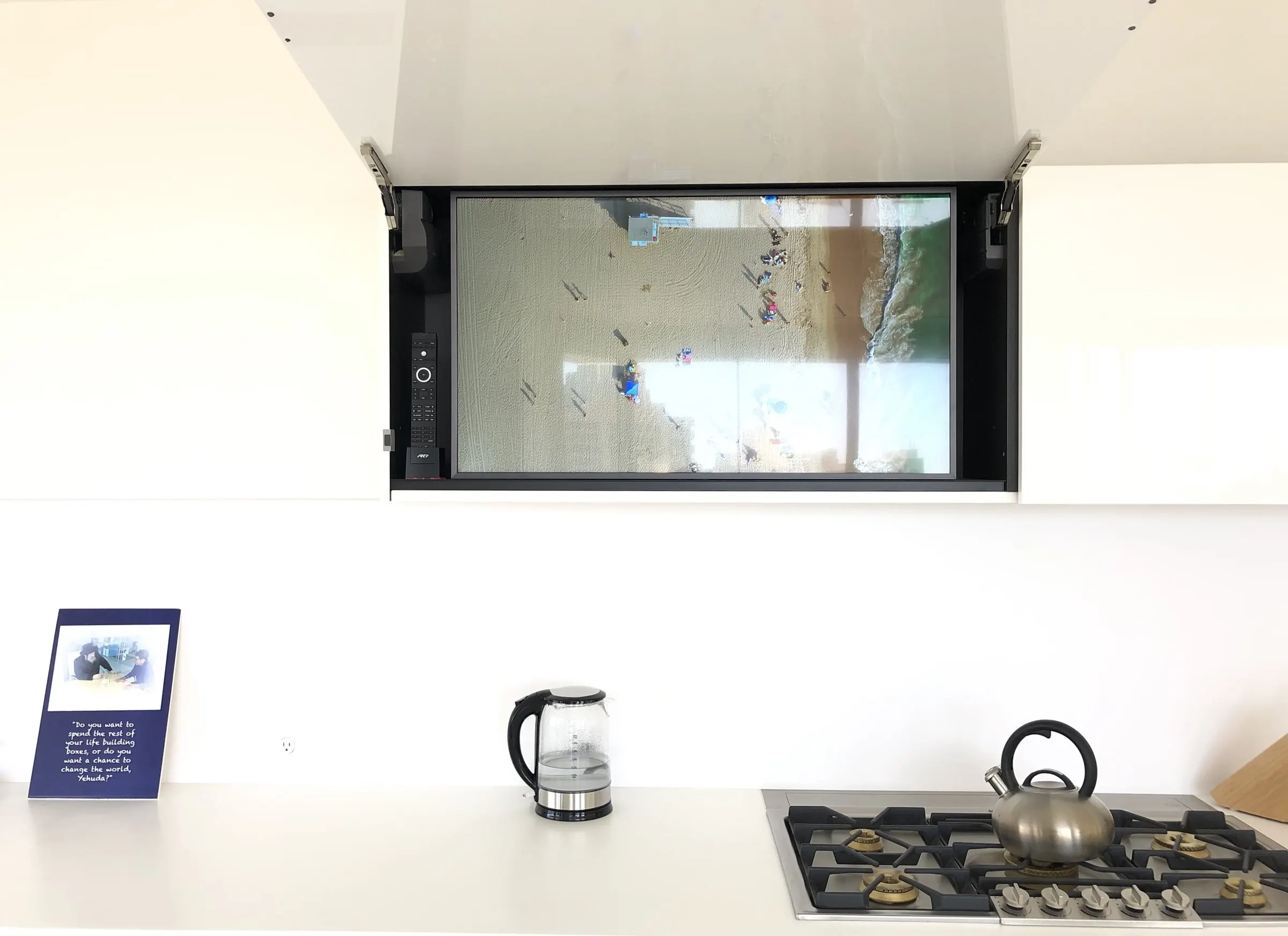 White kitchen with a television revealed from a motorized cabinet above the cooktop