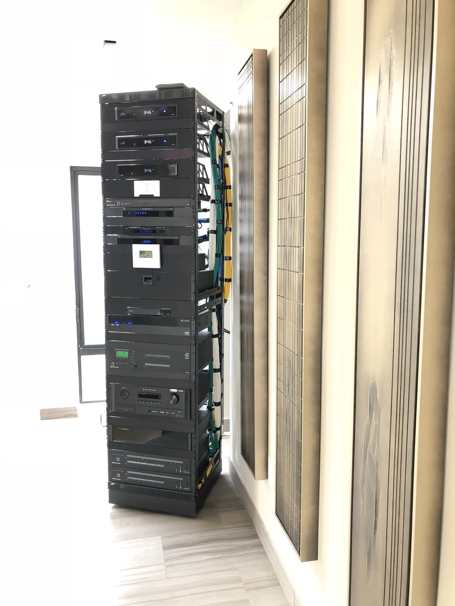 Freestanding equipment rack in a bright hallway next to tall art panels