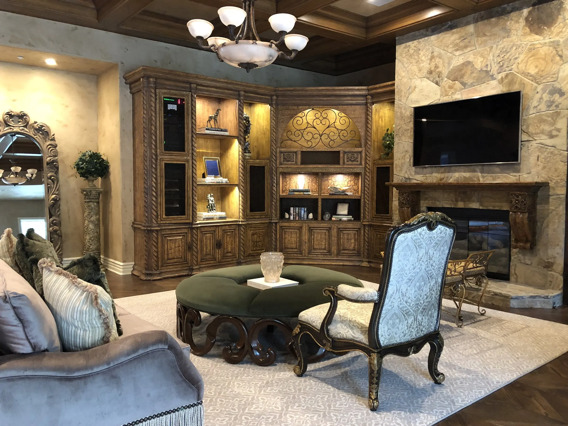 Traditional family room with carved cabinetry and a television beside a stone fireplace